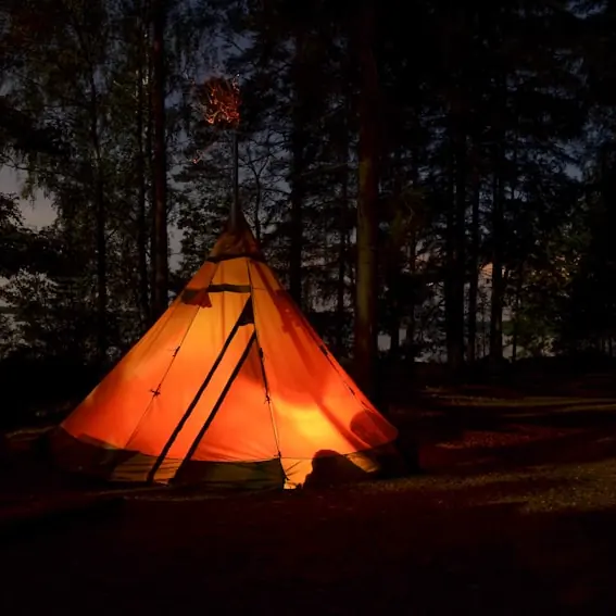 Tente tipi illuminée la nuit en forêt
